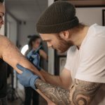 Tattoo artist creating intricate design on client's arm in a studio.