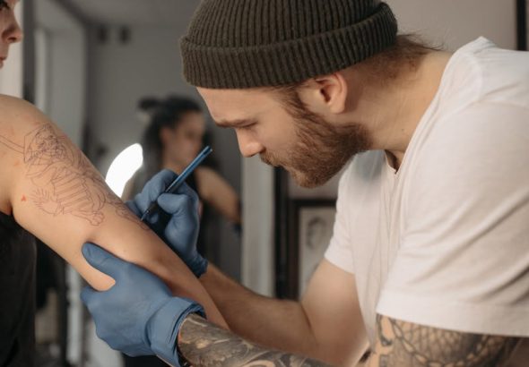 Tattoo artist creating intricate design on client's arm in a studio.