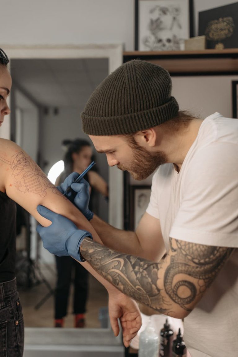 Tattoo artist creating intricate design on client's arm in a studio.