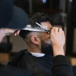a man cutting another mans hair with a pair of scissors
