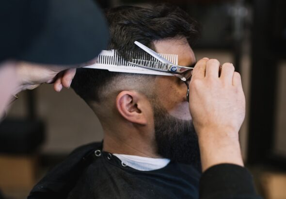 a man cutting another mans hair with a pair of scissors